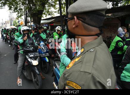 5 septembre 2019, Cipayung, Jakarta, Indonésie : les chauffeurs de moto-taxi en ligne sont prêts à faire la queue pour obtenir des provisions de bénévoles dans la région de Cipayung, Jakarta, le 18 avril 2020. Pas moins de 200 colis alimentaires ont été distribués en ligne aux chauffeurs de motos-taxis, car depuis que la co-pandémie a eu lieu en Indonésie, leurs revenus ont diminué. Depuis les nombreuses commandes précédentes pour le transport, les utilisateurs utilisent maintenant des chauffeurs pour commander de la nourriture, magasiner pour les nécessités quotidiennes ou livrer des marchandises. (Crédit image : © Dasril Roszandi/ZUMA Wire) Banque D'Images