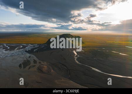 Vue aérienne d'une colline verte et de rivières tressées en Islande au coucher du soleil Banque D'Images