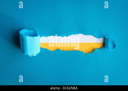 Papier bleu déchiré avec bords rugueux sur papier blanc et jaune. Copier l'espace. Banque D'Images