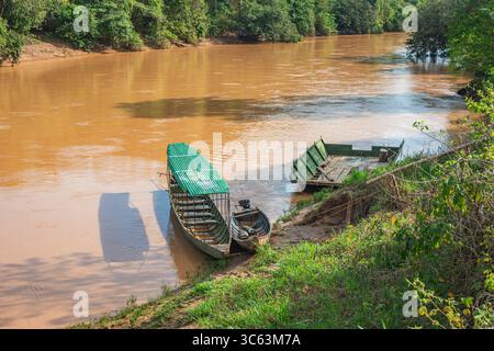 Deux bateaux reposant sur la rive d'une rivière brune à Casanare, entourés d'une végétation luxuriante, représentant une scène de nature tranquille. Banque D'Images