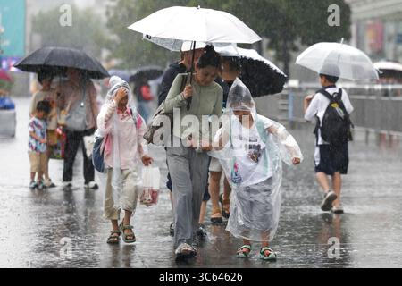 (250731) -- PÉKIN, 31 juillet 2025 (Xinhua) -- les voyageurs marchent sous la pluie près de la gare de Shanghai à Shanghai, dans l'est de la Chine, 30 juillet 2025. Co-May, le huitième typhon de cette année, a touché terre pour la deuxième fois dans la municipalité de Shanghai dans l'est de la Chine mercredi après-midi après avoir touché terre dans la province du Zhejiang tôt mercredi matin, selon l'observatoire météorologique central de Shanghai. Le centre du typhon Co-May (niveau de tempête tropicale) a touché terre deuxième sur la côte du district de Fengxian, Shanghai vers 16 h 40 au moment de toucher terre, la vitesse maximale du vent Banque D'Images