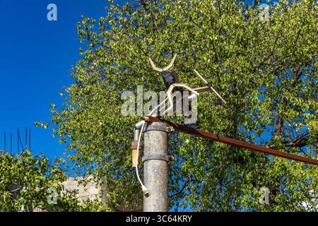 Une vieille antenne de radio et de télévision rouillée montée sur un poteau en béton à côté d'une maison délabrée, une installation pour recevoir la télévision terrestre Banque D'Images