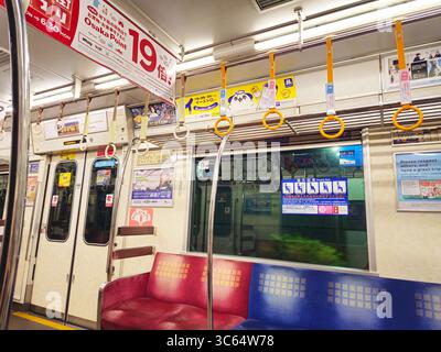 Intérieur vide de voiture de métro d'Osaka avec sièges prioritaires et sangles de suspension, Japon Banque D'Images