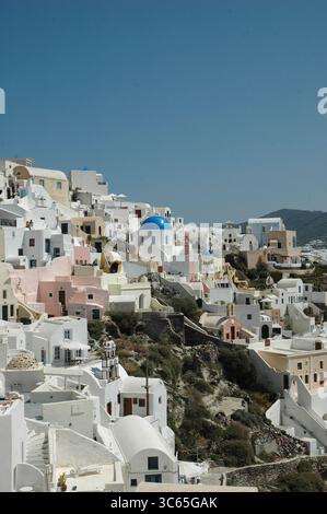 Plan vertical des maisons blanchies à la chaux et des dômes bleus d'Oia, Santorin, sous un ciel bleu clair. Un exemple classique de l'architecture cycladique sur un étourdissement Banque D'Images