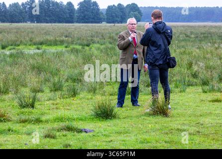 Gorlosen, Allemagne. 31 juillet 2025. Till Backhaus (SPD), le ministre de l'Agriculture, de l'environnement et de la protection du climat de Mecklembourg-Poméranie occidentale, donne un entretien lors d'une visite au projet "conservation des Maures avec les buffles d'eau" dans le cadre de sa tournée estivale. Un troupeau de 120 animaux est actuellement en mouvement dans les zones où le remouillage des landes doit être mis en œuvre. Crédit : Jens Büttner/dpa/Alamy Live News Banque D'Images