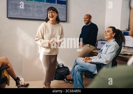 Collègues joyeux appréciant une discussion éclairée dans un environnement de bureau moderne. L'atmosphère détendue encourage une communication efficace et relati Banque D'Images