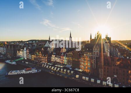 Vue sur la lumière dorée du soleil baigne les bâtiments colorés et les flèches historiques le long de la rivière tranquille dans la vieille ville, Gdansk, Pologne. Banque D'Images