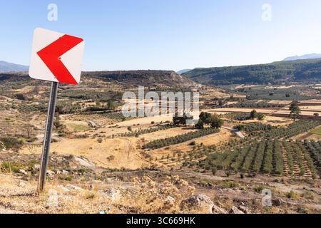 Panneau de signalisation indique à gauche dans la route de la vallée près des champs de ferme, Mugla, Turquie Banque D'Images
