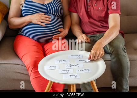 Couple enceinte détendu à la maison choisir le nom pour leur bébé, Focus sélectif Banque D'Images