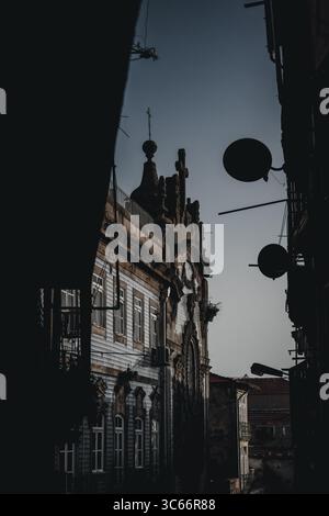 Porto, Portugal - 17 juin 2022 : vue d'un bâtiment historique encadré d'ombres sombres, sa façade ornée témoigne du passage du temps. Banque D'Images