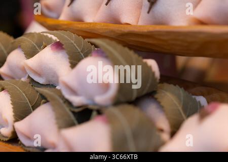 Vue aérienne du délicat mochi sakura rose, chacun enveloppé dans une feuille verte vibrante, mettant en valeur l'art de la confiserie japonaise, Tokyo, Tokyo, Japon. Banque D'Images