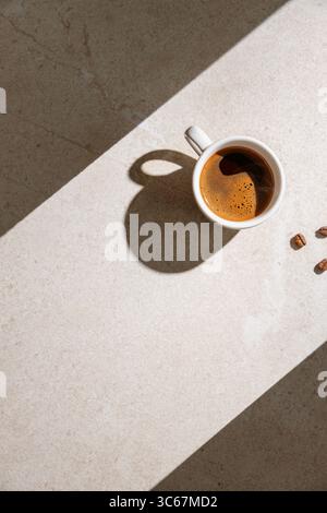 Une tasse de café noir chaud sur une table au soleil Banque D'Images
