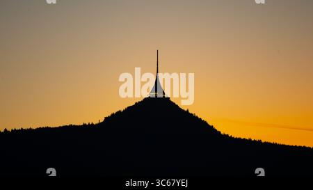 La silhouette de Jested Tower s’élève contre un ciel nocturne vibrant à Liberec, en Tchéquie. La dernière lumière du jour jette une lueur chaude, soulignant la forme distinctive de la tour. Banque D'Images
