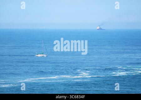 Impressionnant océan Atlantique bleu avec un yacht blanc et un cargo au loin Banque D'Images