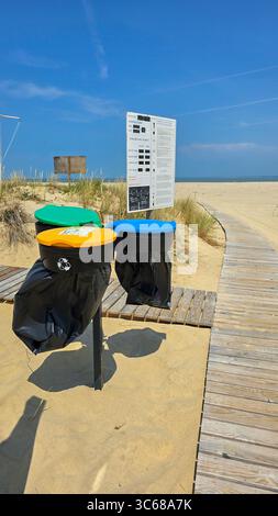 Trois conteneurs de couleurs jaune, bleu et vert pour la collecte séparée des ordures sur la plage publique de l'Atlantique. Format vertical. 13 juin 2025. Verdon-su Banque D'Images