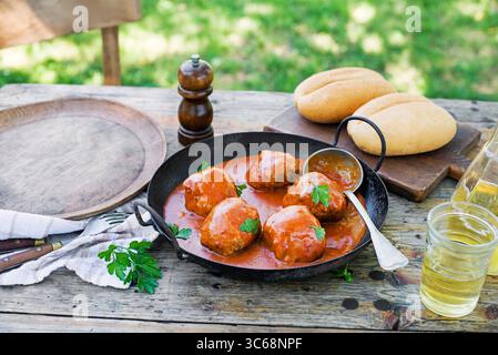 Boulettes de viande frites braisées dans une sauce tomate servies dans le jardin. Manger des boulettes de viande rôties de bœuf dans une sauce tomate. Banque D'Images