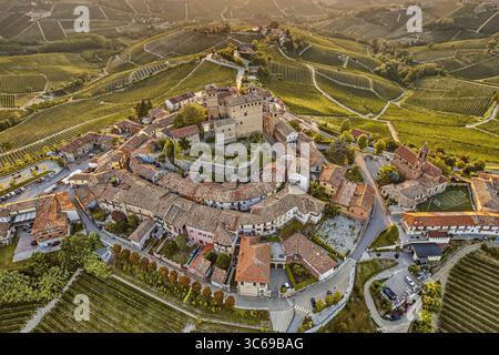 Vue aérienne de l'ancien château, niché parmi les toits en terre cuite et les vignobles verdoyants, baigné dans la lueur chaude du soleil couchant, Serralunga d'Alba, Piémont, Italie. Banque D'Images