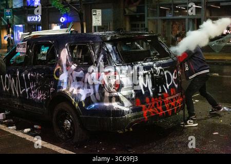 30 mai 2020, Seattle, Washington, États-Unis : un homme frappe un véhicule de police incendié avec un extincteur lors de manifestations en réponse à la mort de George Floyd à Seattle, Washington, le 30 mai 2020. Des milliers de manifestants ont manifesté au milieu de la pandémie de COVID-19, causant des dommages étendus dans le centre de vente au détail du cityÂ€™, ce qui a conduit le gouverneur Jay Inslee à activer plus de 200 membres de la Garde nationale de Washington. (Crédit image : © David Ryder/ZUMA Wire) Banque D'Images