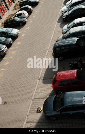 Vue aérienne des voitures et scooters stationnés sur un parking pavé en plein jour. Taches vides marquées en jaune. Subotica, Serbie - 19 juillet 2025. Banque D'Images