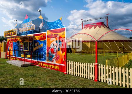 Tout le plaisir du Cirque. Grande tente colorée et affiche de clown en été à Bridport, Dorset. Divertissement familial. Vacances traditionnelles. Nuageux. Banque D'Images
