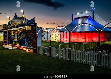 Tout le plaisir du Cirque. Grande tente colorée et affiche de clown en été à Bridport, Dorset. Divertissement familial. Vacances traditionnelles. La nuit. Banque D'Images