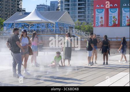 Les gens se rafraîchissent dans une zone brumeuse à Sugar Beach Plaza par une journée ensoleillée près du front de mer. Banque D'Images