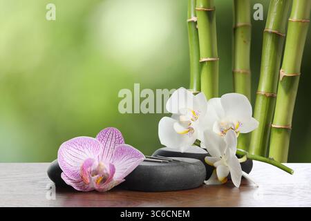 Aiguilles d'acupuncture, pierres de spa et fleurs sur table en bois à l'extérieur Banque D'Images
