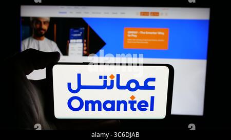 Stuttgart, Allemagne - 06-20-2025 : personne tenant un téléphone portable avec le logo de Oman Telecommunications Company (Omantel) sur l'écran devant la page Web. Banque D'Images