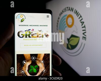 Stuttgart, Allemagne - 06-20-2025 : personne tenant un téléphone portable avec la page web du projet agricole Green Pakistan Initiative sur l'écran devant le logo. Banque D'Images