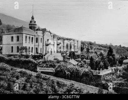Vue du palais du gouverneur allemand à Buea, capitale du Kamerun allemand, lors de l'offensive alliée de 1916 au Cameroun. Positionné sur les pentes du Mont Cameroun, le bâtiment symbolisait l’autorité coloniale avant la prise de la ville par les forces françaises et britanniques. La ligne de chemin de fer visible au premier plan souligne son importance logistique dans le transport des troupes et des fournitures à l'intérieur des terres pendant la campagne ouest-africaine. Banque D'Images