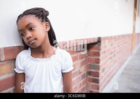 Fille afro-américaine debout à côté du mur de briques sur le trottoir avec de longues tresses, espace de copie. Jeunesse, urbain, contemplatif, innocence, naturel, sortie Banque D'Images
