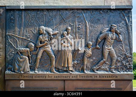 ALEXANDRIA, Virginie — Une sculpture en relief en bronze représente une famille fuyant l'esclavage au mémorial du cimetière des Contrabands et des Freedmen, avec l'inscription « fuir l'esclavage pour un sanctuaire et la liberté à Alexandrie ». L'œuvre du sculpteur local Joanna Blake fait partie du mémorial dédié en 2014 à 1 711 Afro-Américains morts entre 1864-1869 et enterrés dans le cimetière historique. Le cimetière est établi en mars 1864 sur des terres confédérées confisquées pour servir la communauté de contrebande et d'affranchis d'Alexandrie pendant la guerre de Sécession. Le site a acquis une importance nationale à Decemb Banque D'Images