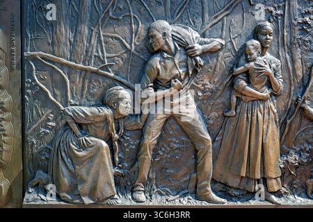 ALEXANDRIA, Virginie — Une sculpture en relief en bronze représente une famille fuyant l'esclavage au mémorial du cimetière des Contrabands et des Freedmen, avec l'inscription « fuir l'esclavage pour un sanctuaire et la liberté à Alexandrie ». L'œuvre du sculpteur local Joanna Blake fait partie du mémorial dédié en 2014 à 1 711 Afro-Américains morts entre 1864-1869 et enterrés dans le cimetière historique. Le cimetière est établi en mars 1864 sur des terres confédérées confisquées pour servir la communauté de contrebande et d'affranchis d'Alexandrie pendant la guerre de Sécession. Le site a acquis une importance nationale à Decemb Banque D'Images