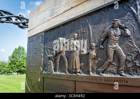 ALEXANDRIA, Virginie — Une sculpture en relief en bronze représente une famille fuyant l'esclavage au mémorial du cimetière des Contrabands et des Freedmen, avec l'inscription « fuir l'esclavage pour un sanctuaire et la liberté à Alexandrie ». L'œuvre du sculpteur local Joanna Blake fait partie du mémorial dédié en 2014 à 1 711 Afro-Américains morts entre 1864-1869 et enterrés dans le cimetière historique. Le cimetière est établi en mars 1864 sur des terres confédérées confisquées pour servir la communauté de contrebande et d'affranchis d'Alexandrie pendant la guerre de Sécession. Le site a acquis une importance nationale à Decemb Banque D'Images