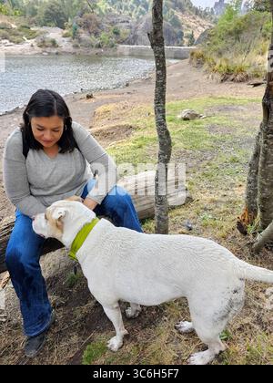 Une femme adulte latina passe du temps à l'extérieur avec son chien de soutien émotionnel comme thérapie pour le stress et l'anxiété Banque D'Images
