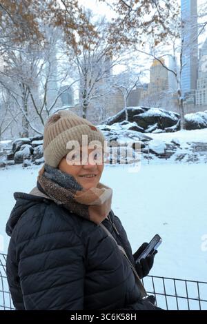 Femme marchant à travers Central Park couvert de neige, New York Banque D'Images