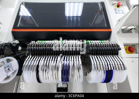 Les alimentateurs de bande avancés sur la machine de saisie et de placement SMT fonctionnent efficacement dans la chaîne d'assemblage de haute technologie pendant le processus de fabrication dans l'usine d'électronique Banque D'Images