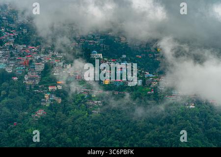Mousson brumeuse vue matinale de Darjeeling, une station de colline célèbre dans le Bengale occidental, Inde. Des nuages denses planent au-dessus de maisons colorées à flanc de colline entourées. Banque D'Images