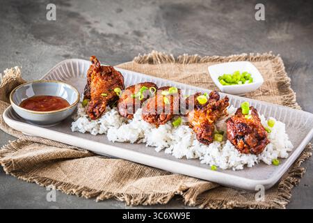 Ailes de poulet frites avec sauce sur riz sur fond de béton gris rustique, espace de copie Banque D'Images