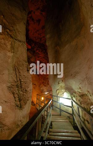 Les visiteurs naviguent sur une promenade en bois à travers un étroit passage de grotte, entouré de formations rocheuses accidentées et d'un éclairage ambiant créant un a intrigant Banque D'Images