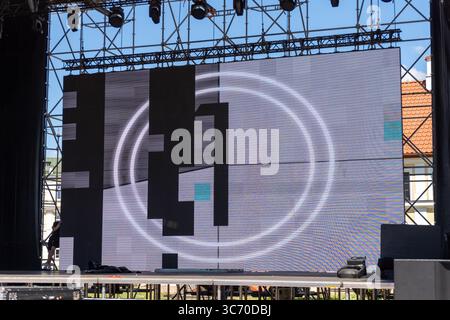 Un grand écran LED modulaire affiche des séquences vidéo vibrantes lors d'un concert extérieur énergique, illuminant la nuit avec des visuels dynamiques. Banque D'Images