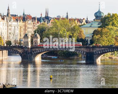 Tramway traversant le point de repère Most Legií (pont de la Légion) dans le centre-ville de Prague. Transports en commun utilisant les véhicules Tatra. Rivière Vltava et maisons. Banque D'Images