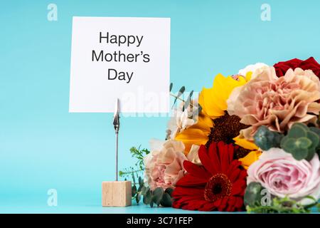 Bonne carte de fête des mères et bouquet de fleurs mélangées sur fond bleu Banque D'Images