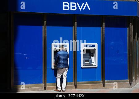 ALICANTE, ESPAGNE - 16 AVRIL 2025 : la personne utilise un distributeur automatique de billets à la succursale de la banque BBVA à Alicante, Espagne. BBVA est l'un des plus grands groupes bancaires en Espagne. Banque D'Images
