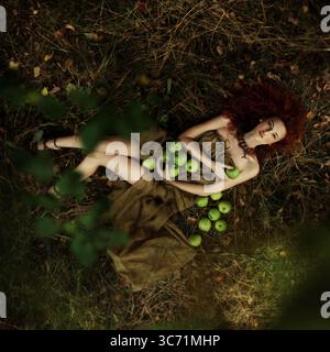 Une belle femme dans la nature entourée de pommes vertes fraîches et vibrantes dans un cadre paisible Banque D'Images