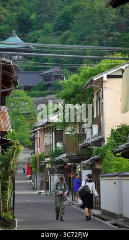 Scène de rue sur l'île de Miyajima, au Japon, montrant des maisons traditionnelles et des gens marchant près du quartier du temple de Daisho-in. Banque D'Images