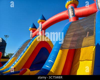 Toronto, ON, Canada – 31 mai 2024 : les familles se rassemblent autour de grands toboggans gonflables et de parcours d’obstacles lors d’un événement pour enfants par un après-midi ensoleillé. Banque D'Images