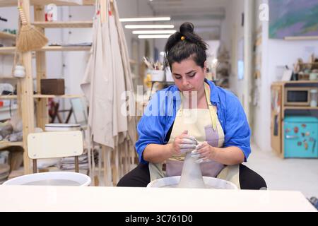 Ceramist molding clay on pottery wheel in workshop Banque D'Images
