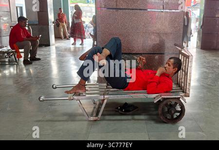 Mumbai, Maharashtra, Inde. 1er août 2025. Un porteur de chemin de fer, également connu sous le nom de coolie ferroviaire, est vu en train d'utiliser son téléphone portable alors qu'il était allongé sur un chariot à bagages à l'intérieur d'une gare de Mumbai. Les porteurs de chemin de fer aident les passagers à transporter des bagages lourds à la gare. Ils aident également au chargement et au déchargement des caisses qui arrivent dans les trains de différentes villes. (Crédit image : © Ashish Vaishnav/SOPA images via ZUMA Press Wire) USAGE ÉDITORIAL SEULEMENT ! Non destiné à UN USAGE commercial ! Banque D'Images