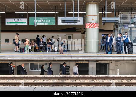 Nagano, Japon - 22 avril 2025 : le quai de la gare de Nagano est en train d'attendre des passagers alors que le personnel ferroviaire marche dans le passage sous le pl Banque D'Images